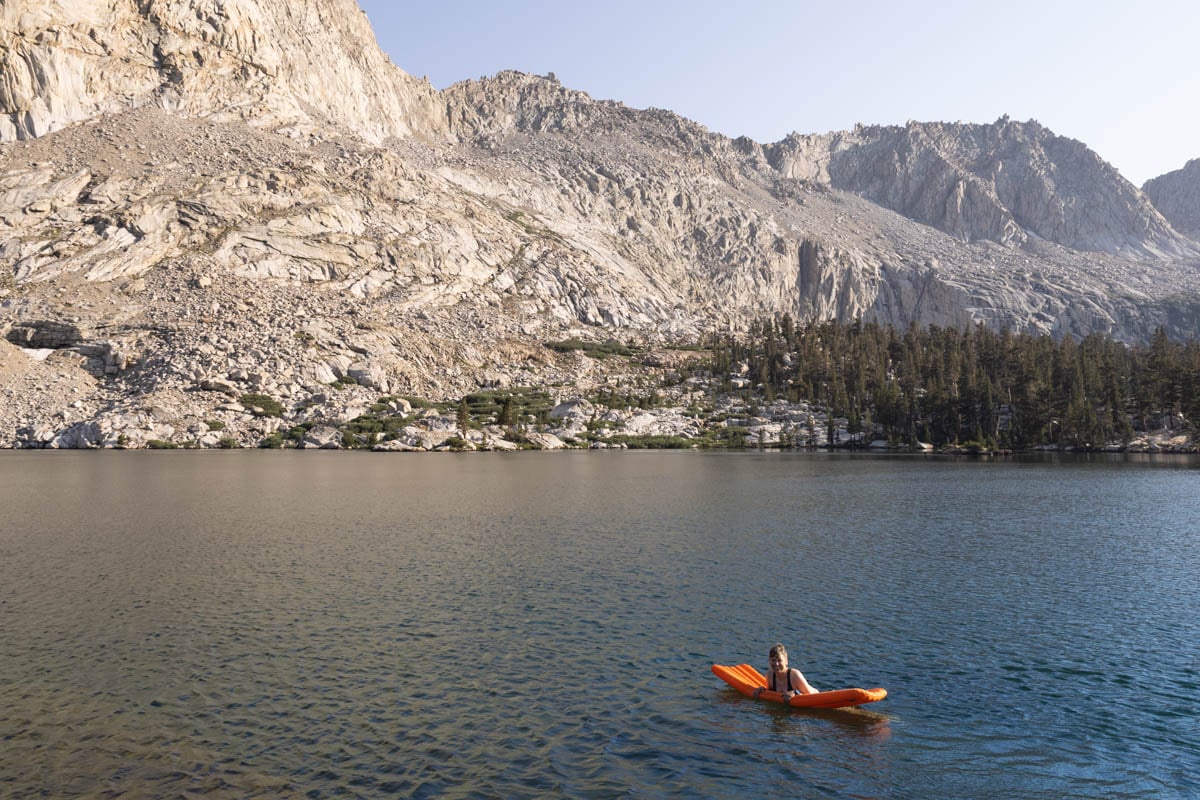 Kristen Bor swimming in a lake in Sequoia National Park using a sleeping pad as a float