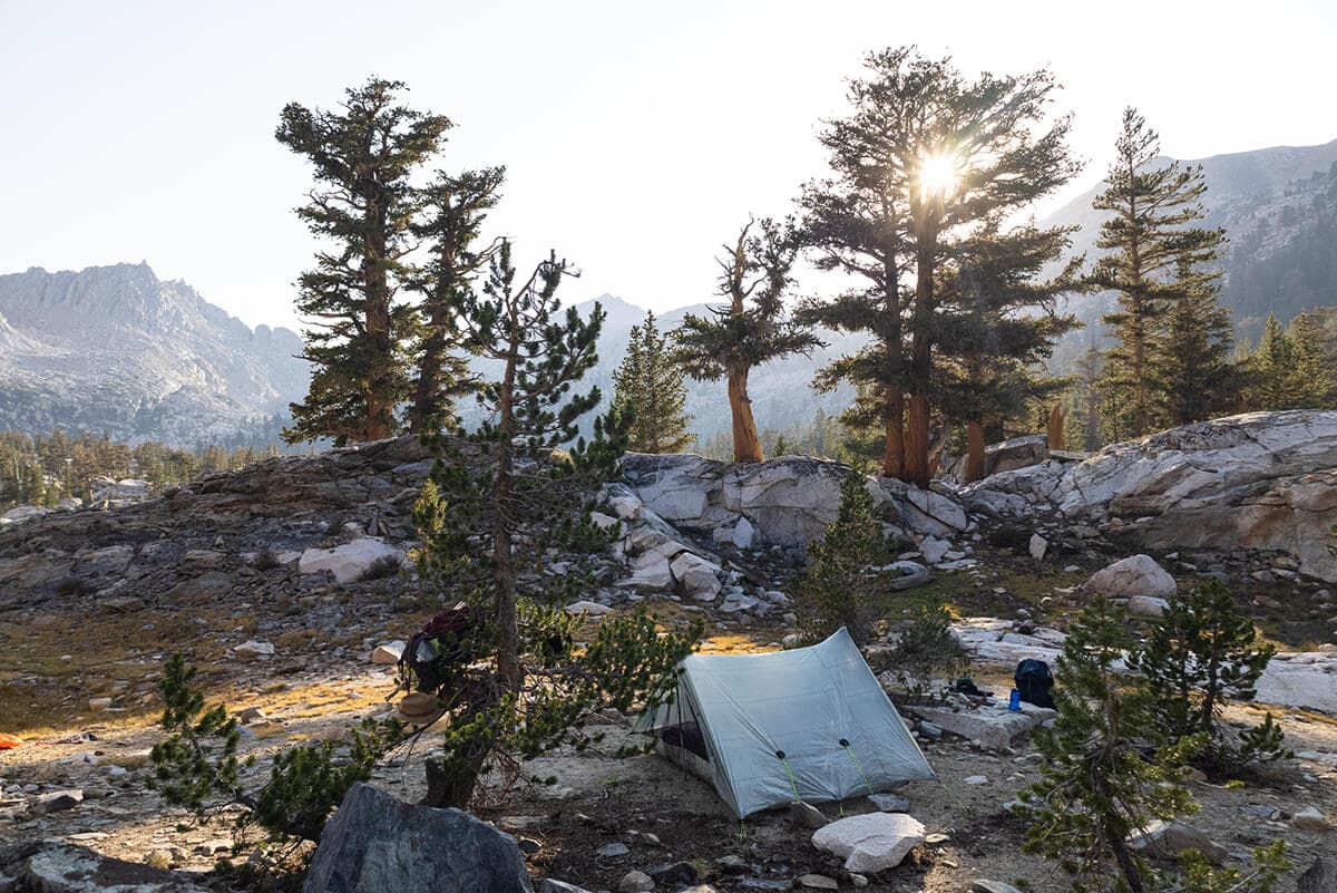 Tent pitched at sunset with mountains in background