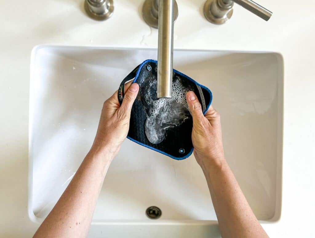 Washing Kula Cloth pee rag in sink with soap and water