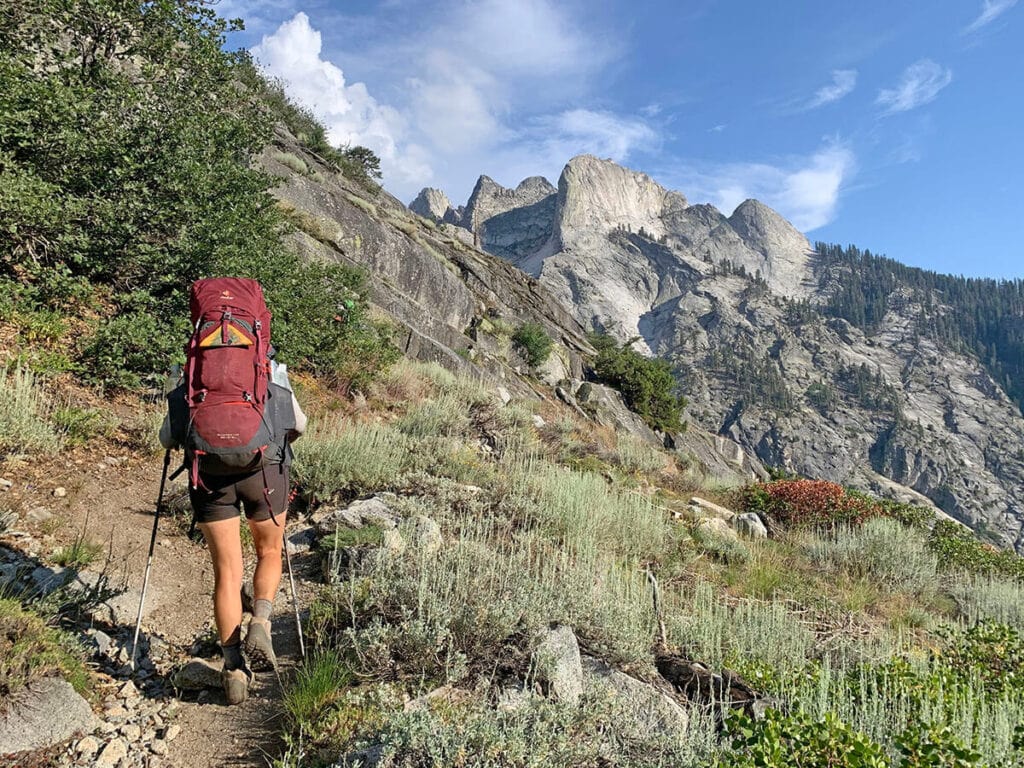 A woman backpacks through Sequoia National Park wearing a red backpacking pack