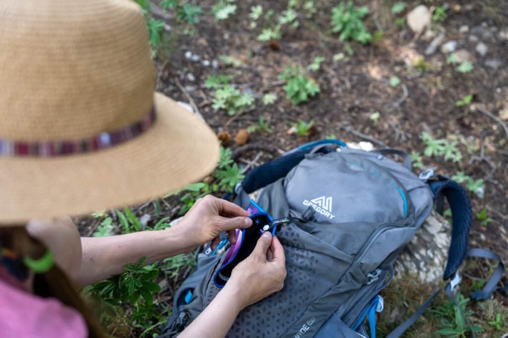 Kristen Bor clipping a Kula Cloth pee rag to the outside of a hiking backpack