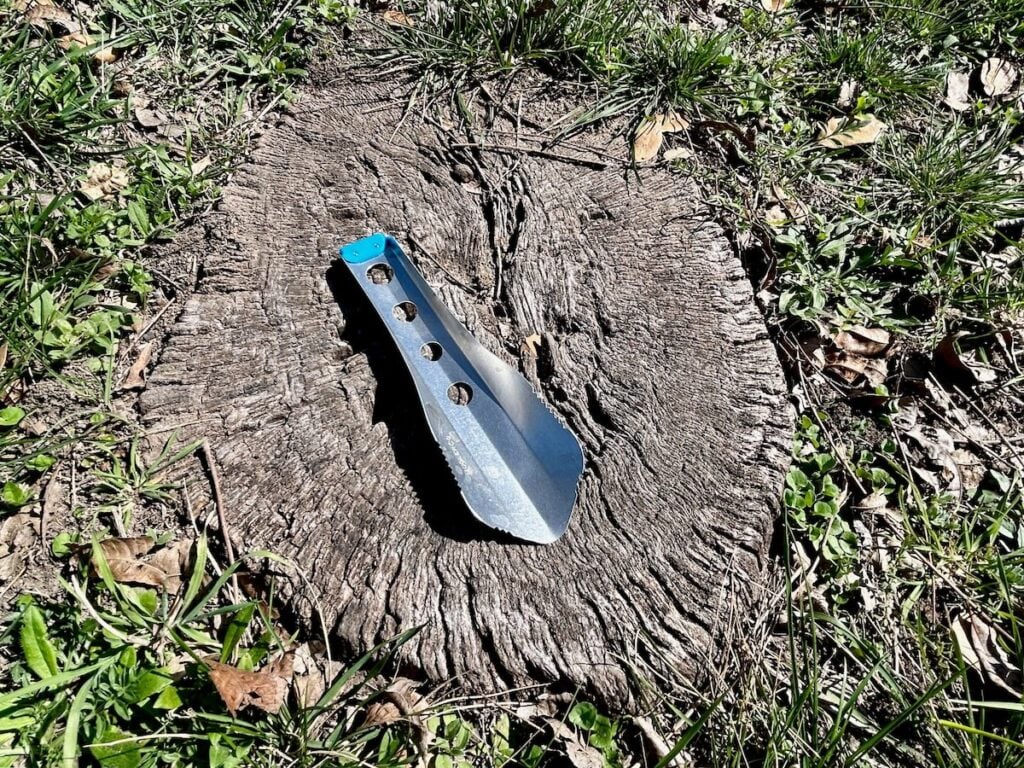 Backpacking trowel resting on tree stump