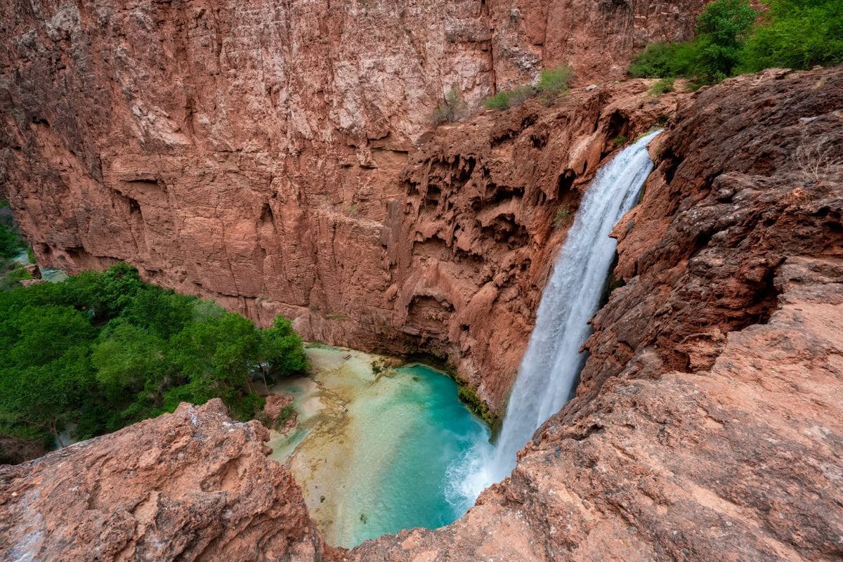 Top of Mooney Falls in Havasupai pouring into turquoise pool of water