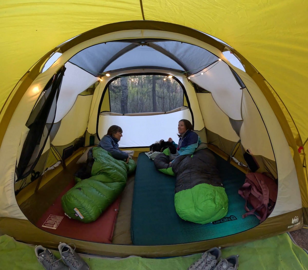 Two women inside sleeping bags inside the REI Base Camp 4 Tent